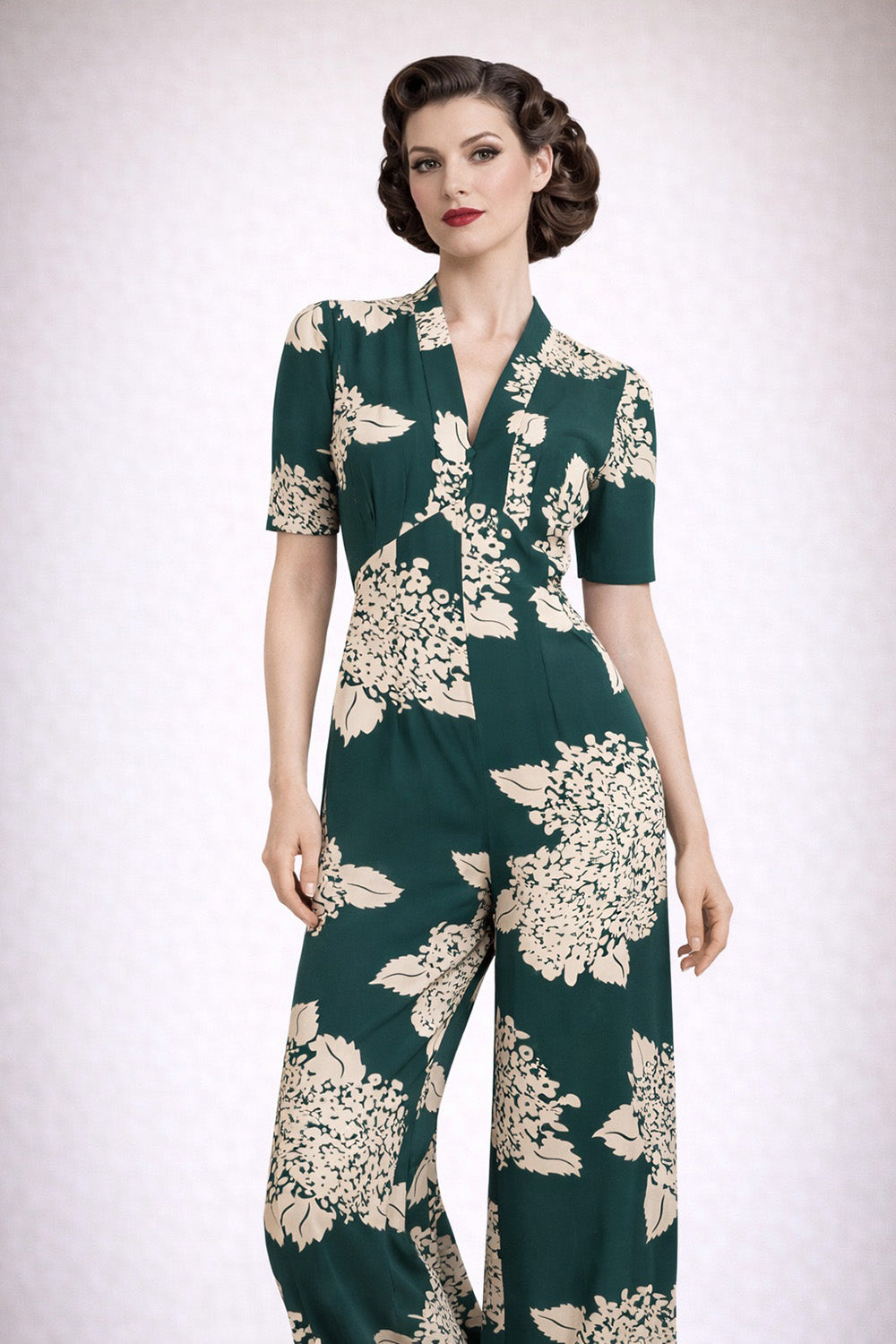 Woman wearing a green floral jumpsuit on a white background