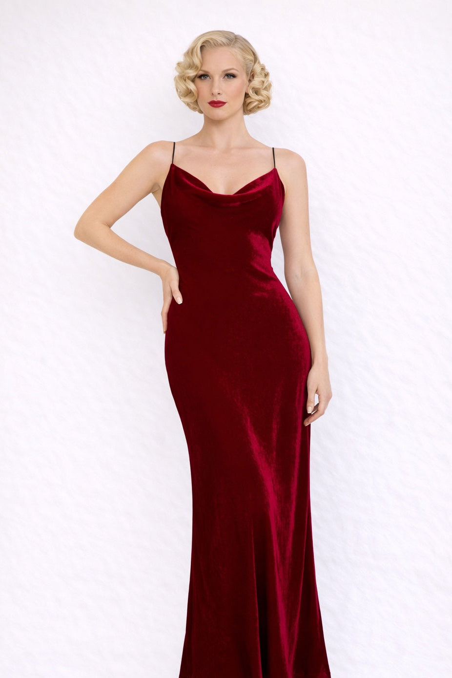Woman wearing a red velvet full length dress against a white background