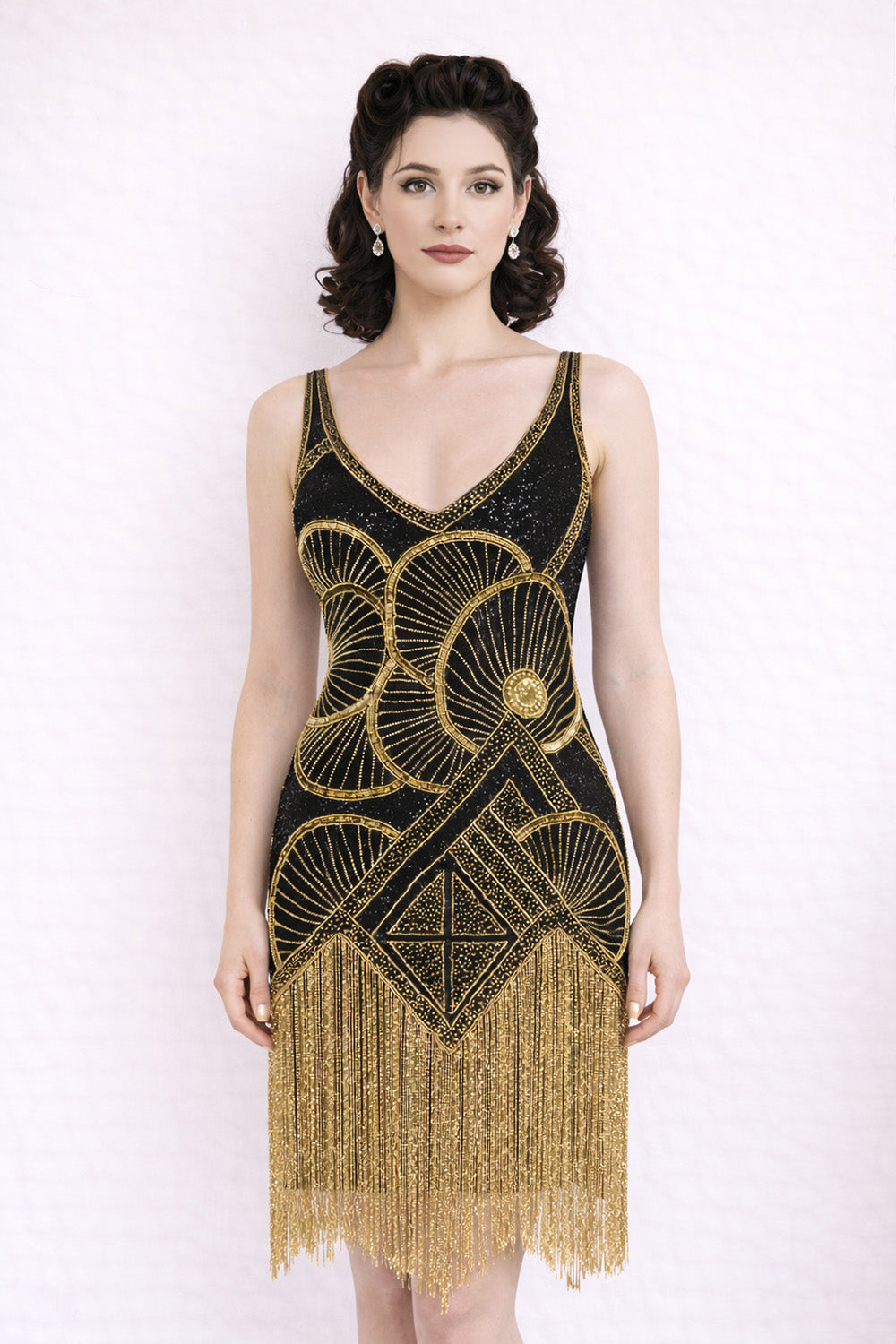 Black and gold 1920s vintage beaded tassel flapper dress worm by model on white bac
kground