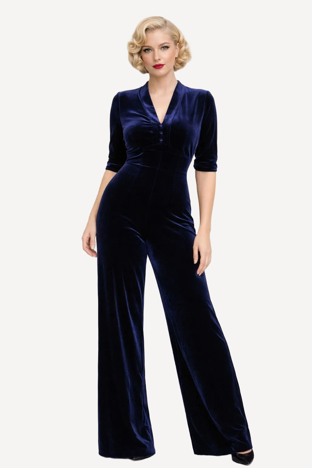 Woman wearing a navy velvet jumpsuit on a white background