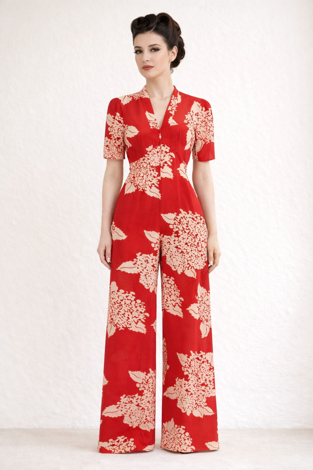 Woman wearing a red floral jumpsuit on a white background