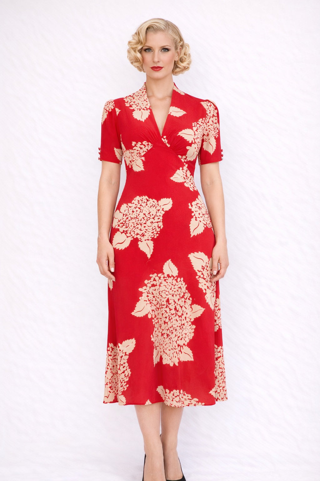 Woman wearing a red dress with white floral pattern on a white background