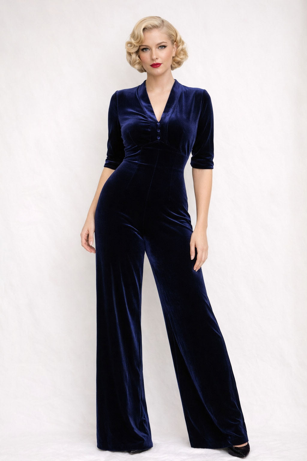 Woman wearing a navy velvet jumpsuit on a white background
