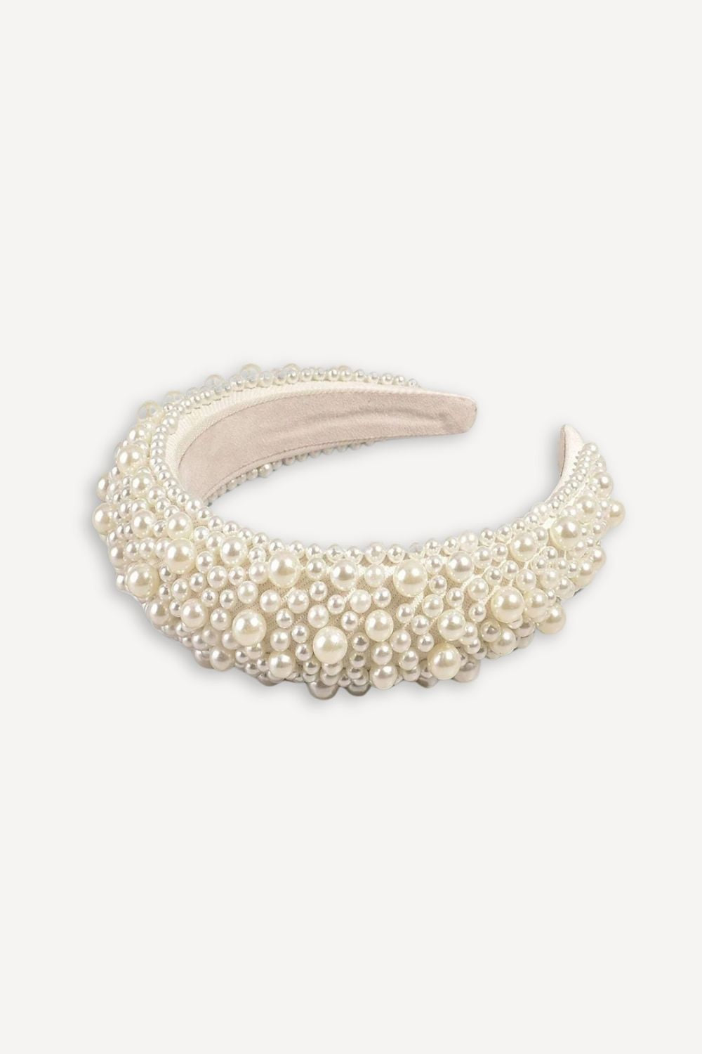 A wide, curved pearl headband with layered faux pearls and small bead accents on a light gray background.