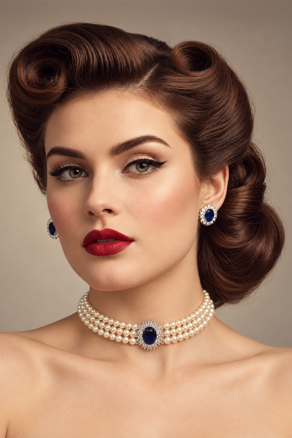 A woman with a vintage 1950s hairstyle wearing a pearl choker necklace with a central blue gemstone, matching blue and pearl stud earrings, and red lipstick, photographed against a neutral beige background.
